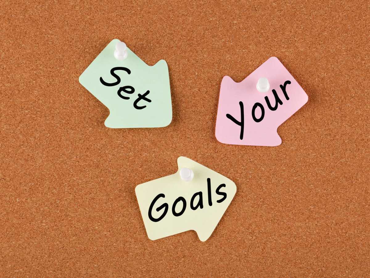 Three sticky notes pinned on corkboard saying "set your goals."
