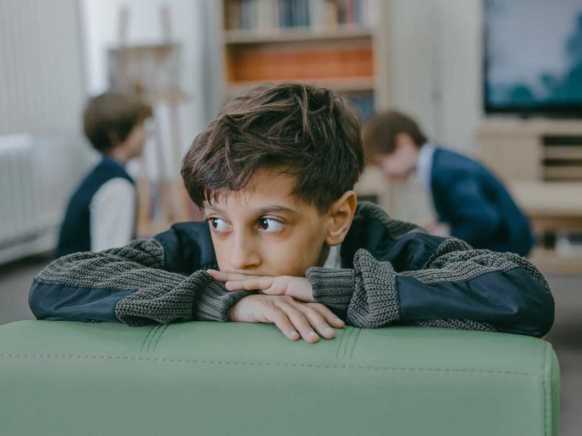 A boy isolates himself from his peers feeling unsure of himself and having low self-esteem.
