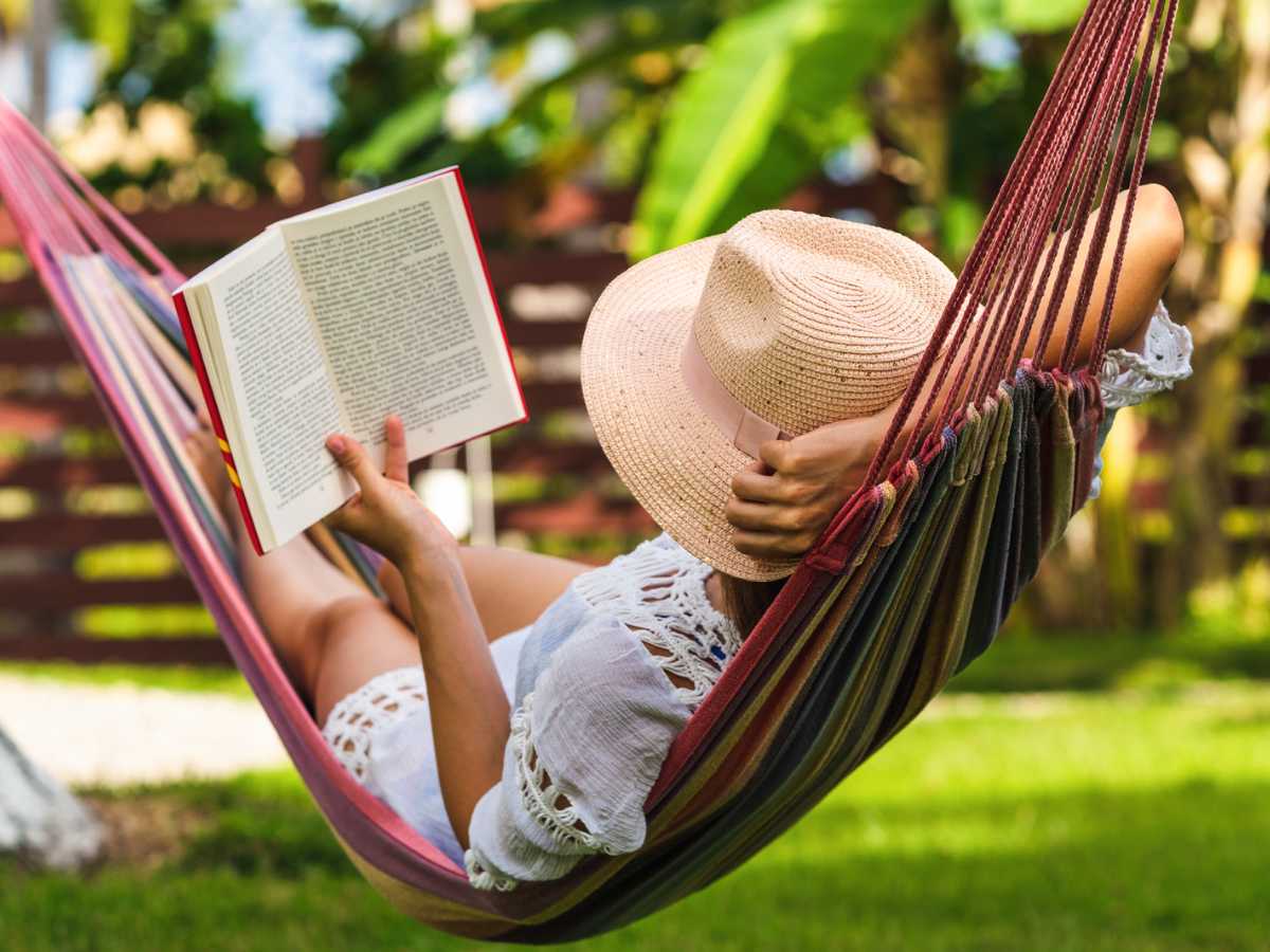 Woman relaxing on a hammock reading a book.